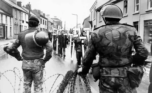 1972年2月6日，北爱尔兰的示威者游行经过英国军队。
